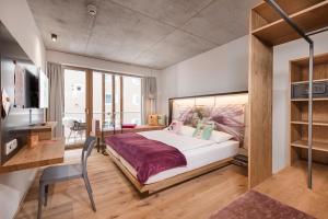 a bedroom with a large white bed and a desk at Hotel Blü Gastein in Bad Hofgastein