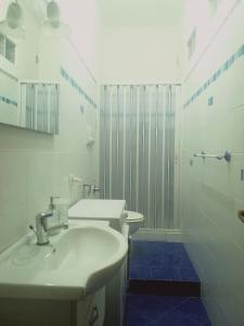 een witte badkamer met een wastafel en een douche bij By the sea in Scario in Scario