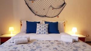 a bed with blue and white pillows and two lamps at Guest House San Vito Lo Capo in San Vito lo Capo