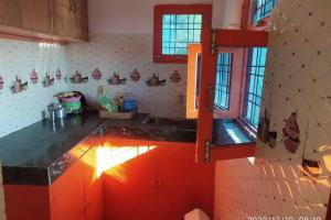 a kitchen with red cabinets and a counter top at MangalMurti Himalyan Homestay in Hawālbāgh