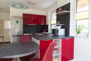a kitchen with red cabinets and a table with red chairs at Fewo-Waterkant in Dranske