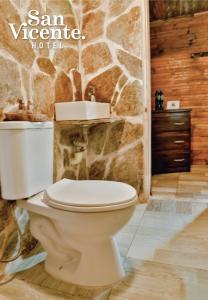 baño con aseo blanco y pared de piedra en Hotel Termales San Vicente, en Santa Rosa de Cabal