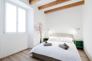 a white bedroom with a bed with two stuffed animals on it at Spazio 77 - The House Of Travelers in Como