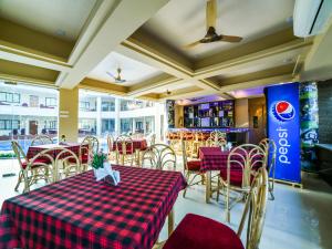 een restaurant met een tafel en stoelen met een rood gecontroleerd tafelkleed bij The Center Court Resort & Spa in Varca