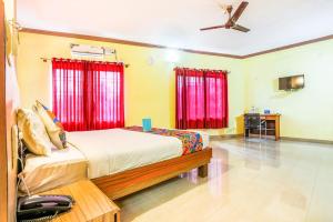 a bedroom with a bed with red curtains at Hotel City Comforts in Madikeri
