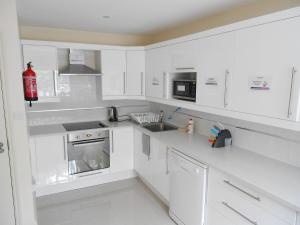 a white kitchen with white cabinets and appliances at Mapesbury Hostel London in London