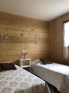 two beds in a room with wooden walls at Les Chalets de la Garenne in La Ferté-Beauharnais +2 photos