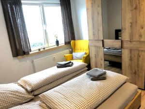 2 Betten in einem Zimmer mit gelbem Stuhl in der Unterkunft Ferienwohnung Tannenglück in Schmallenberg