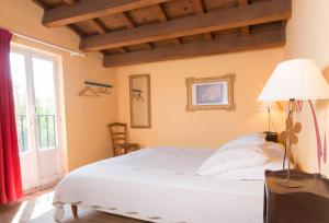 ein Schlafzimmer mit einem weißen Bett und einem Fenster in der Unterkunft Les Gîtes du Domaine Grand Guilhem in Cascastel-des-Corbières