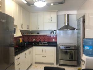 une cuisine avec des armoires blanches et un four à plaques de cuisson dans l'établissement Apt frente para o mar - Prainha, Arraial do Cabo, à Rio de Janeiro 4 autres photos