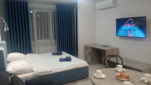 Schlafzimmer mit einem Bett, einem Tisch und einem TV in der Unterkunft Apartament YesCity! in Uschhorod