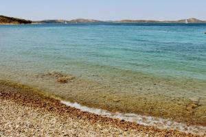 a beach with blue water and a rocky shore at Holiday Home Subasic in Zlarin