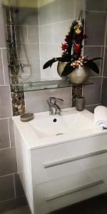 a bathroom sink with a vase with flowers in it at Habitation Noëlesse - vue mer à Marie-Galante - authentique et romantique in Beauregard +33 photos