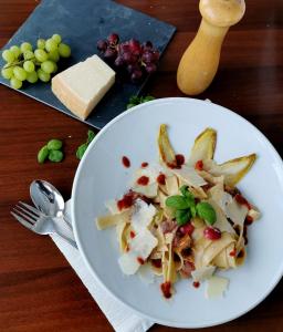 a plate of pasta with cheese and grapes on a table at Hotel & Chalets Herrihof in Todtnauberg