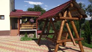 una struttura di gioco in legno con un edificio sullo sfondo di Pensiunea Valea Ursului a Cîmpulung