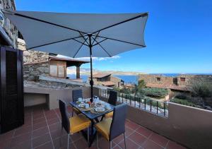 einen Tisch und Stühle mit Sonnenschirm auf dem Balkon in der Unterkunft SAN TEODORO PUNTA EST AMPIO TRILOCALE VISTA MARe in Capo Coda Cavallo