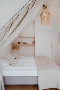 Habitación blanca con cama y lámpara de araña. en Forest House Pobierowo, en Pobierowo