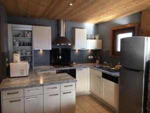a kitchen with white cabinets and a refrigerator at Chalet Les Bouleaux, la montagne des lamas in La Bresse