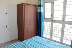a bedroom with a bed and a cabinet and windows at Nature's Lap Homestay in Igatpuri