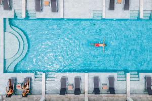 a person swimming in a large swimming pool at Khaolak Emerald Surf Beach Resort and Spa - SHA Extra Plus in Khao Lak