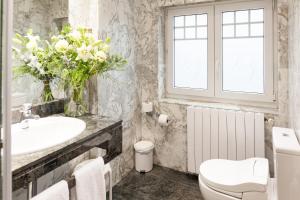 a bathroom with a sink and a toilet and a vase of flowers at La Galería in Donostia-San Sebastián