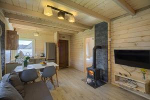 a living room with a fireplace and a table and a television at Domki Bajeczny Łan in Tylicz