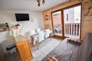 un salon avec une table à manger et une télévision dans l'établissement Le Pied des Pistes A13, Joli Studio tout confort 4 pers, vue vallée imprenable, DRAPS NON COMPRIS, à Saint-Jean-dʼAulps