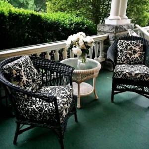 two chairs and a table with a vase of flowers on a porch at The Lion and the Rose Bed and Breakfast in Asheville