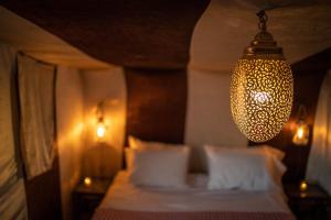 a bedroom with a bed and a chandelier at M'hamid Bivouac - Chez Naji in Mhamid