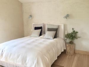 a white bed with two pillows and a plant on it at La Ferme de Saint Christeau in Auch
