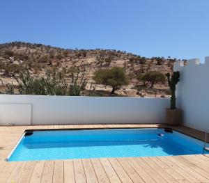 a blue swimming pool on a wooden deck with a mountain at ESCALE PARADIS 10 pers 4 ch 3 sdb piscine in Aourir