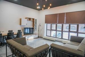 a living room with chairs and a kitchen with windows at Sulu Hostel in Astana