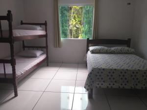a bedroom with two bunk beds and a window at Casa Aconchegante a 20 Minutos do Centro de Paraty in Paraty