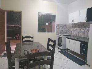 uma cozinha com uma mesa e uma mesa e cadeiras em Casa Aconchegante a 20 Minutos do Centro de Paraty em Paraty