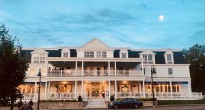 a large white house with a porch and a car parked in front at Mills Park Hotel in Fairborn