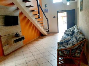 a living room with a couch and a staircase at Casa de férias in Caraguatatuba