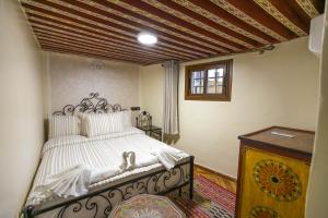 1 dormitorio con cama blanca y techo de madera en Dar El Ouedghiri, en Fez