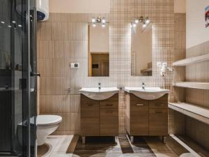 a bathroom with two sinks and a toilet and a mirror at Apartamenty Góralska Pasja Krupówki 37 in Zakopane