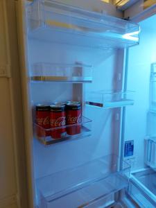 an open refrigerator with soda cans in it at Mlociny Apartment in Warsaw