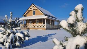 a house covered in snow in front of a tree at Villa Monciske in Palanga