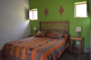a bedroom with a large bed with green walls at Hosteria La Morada in Tilcara