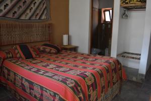 Un dormitorio con una cama con una manta de colores. en Hosteria La Morada en Tilcara