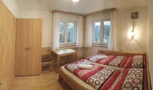 a bedroom with a bed and a desk and windows at U Kapličky in Rokytnice nad Jizerou