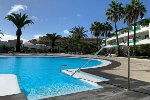 an empty swimming pool with palm trees and buildings at Apartamento Bastian Casas Verdes in Costa Teguise