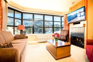 a living room with a couch and a fireplace and a tv at Sundial Hotel in Whistler