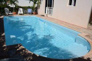 舍爾謝的住宿－Appartement de Standing en Martinique，一座房子前面的蓝色海水大型游泳池