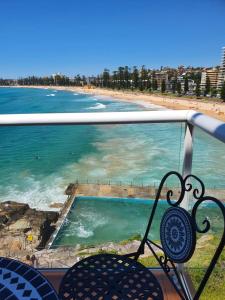 a view of a beach and the ocean from a balcony at Manly Waterfront Beach Stay in Queenscliff