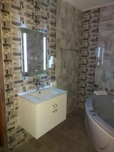 a bathroom with a sink and a tub and a mirror at Sweet Life Family Hotel in Tsigov Chark