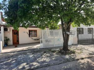 a white fence and a tree in front of a house at Casa da Karin in Torres