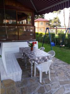 a patio with a table and chairs and a swing at Вила Сладък Живот in Tsigov Chark